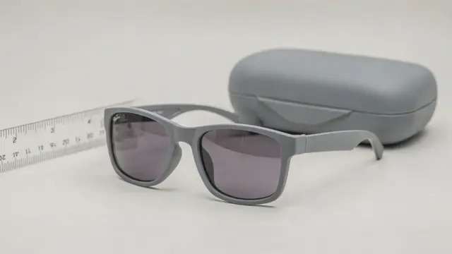 Bruchsichere Kindersonnenbrille auf hellem Tisch mit Etui und Maßstab