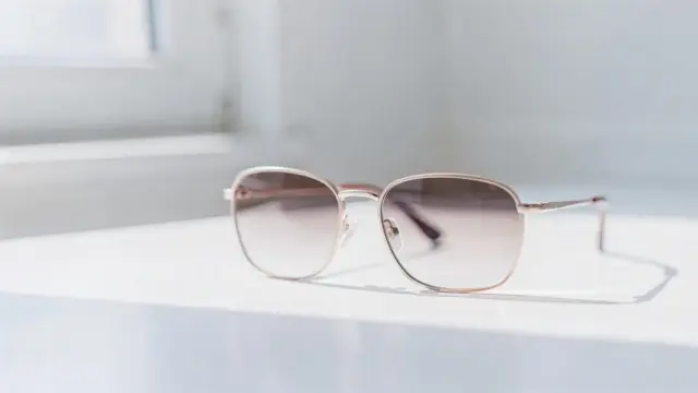 Getönte Sonnenbrille auf hellem Untergrund zum Thema Lichtempfindlichkeit und Sonnenschutz