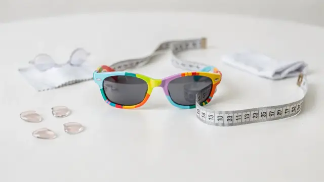 Kindersonnenbrille in passender Größe mit Maßband auf hellem Tisch für sicheren Sitz