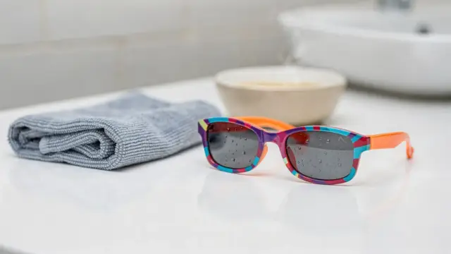Beschlagene Kindersonnenbrille mit Mikrofasertuch beim Entfernen von Kondenswasser