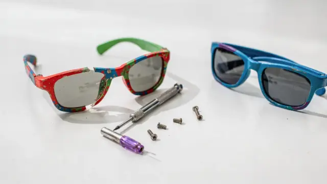 Kindersonnenbrillen reparieren oder neu: defekte Sonnenbrille mit Werkzeug auf hellem Untergrund