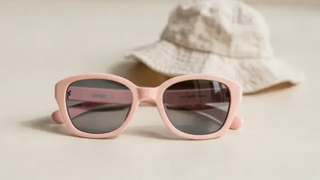 UV400 Kindersonnenbrille auf neutralem Untergrund mit Sonnenhut als Symbol für Schutz und Kennzeichnung.