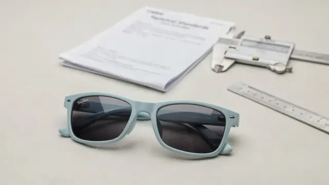 Kindersonnenbrille neben Normdokument und Messwerkzeug zur EN-Norm für Kindersonnenbrillen